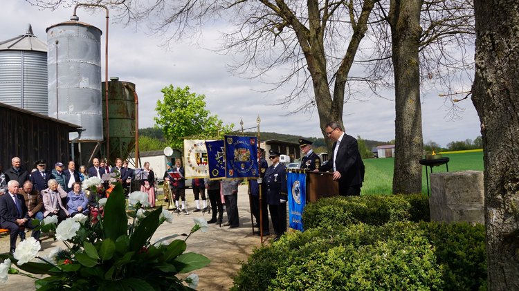 Zuhörer, Musiker und Fahnenträger an einem unscheinbaren Steinkreuz am dörflichen Ortsrand: Gedenken an die Tragödie von Unterbrunn
