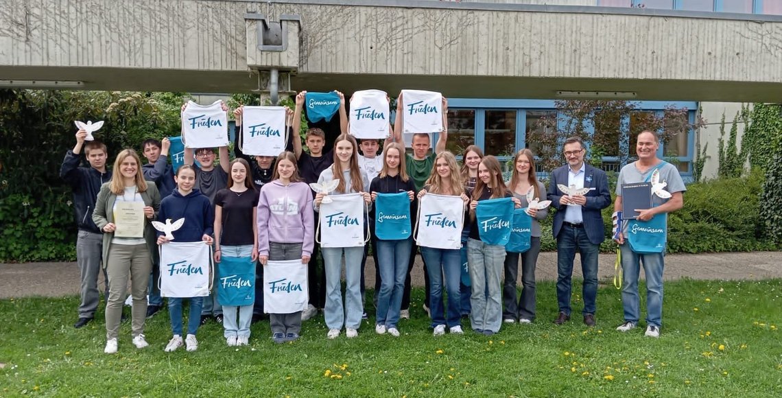 Schüler halten weiße und blaue Taschen mit Volksbund-Logo: Auszeichnung der Realschule Regenstauf für den zweiten Platz im Schülerwettbewerb.