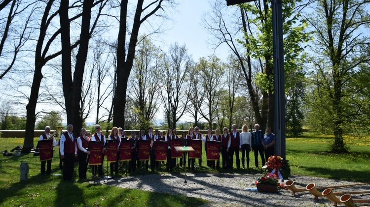 Musikanten auf einer Wiese mit Steinkreuzen: Gedenken anlässlich des 80. Jahrestags des Kriegsendes mit Angehörigen des gefallenen Oberst Jakob von Bargen, der auf der Kriegsgräberstätte Cheb bestattet ist. Die Veranstaltung wurde umrahmt durch die "Steller Musikanten" aus der Gemeinde Stelle im Landkreis Harburg (Niedersachsen). 