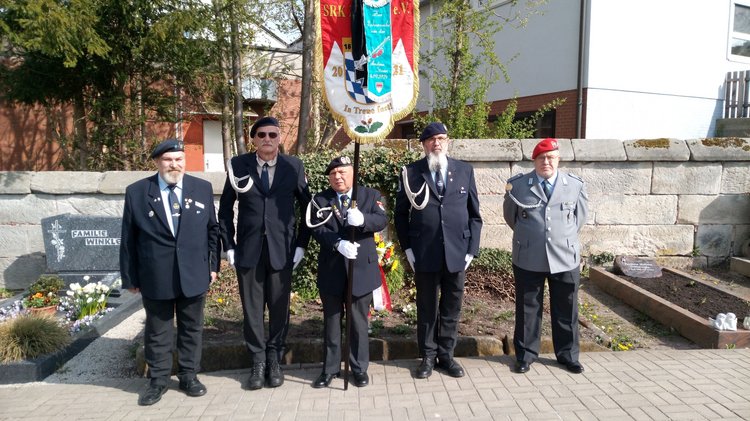 Personen in Vereinskleidung und Uniform vor einem Grab: Erinnerung an das Kriegsende 1945 in Cadolzburg (Mittelfranken).