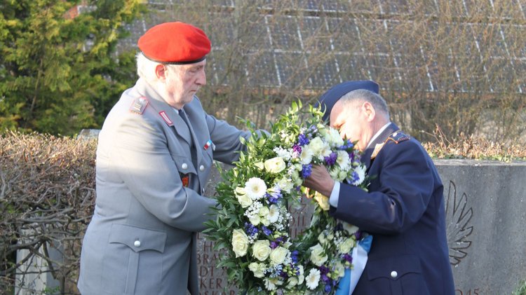 Zwei Uniformierte legen einen Kranz nieder: Erinnerung an die Zerstörung des Renaissanceschlosses Wässerndorf.
